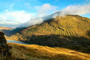 Picture of a view over a mountain with some clouds on one flank