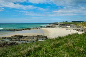 Picture of a sandy beach in a bay backed by dunes