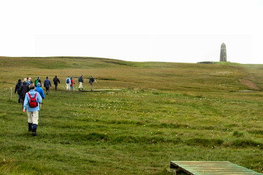 Picture of a group of walkers following a vague path towards a monument